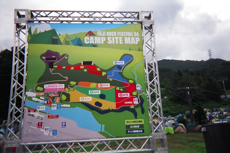 キャンプサイトの入り口にある案内板。通常、「レディース・サイト」「Aサイト」「Bサイト」は、前夜祭の夕方までには埋まってしまいます。入り口から「Dサイト」まで徒歩5～10分。「Cサイト」「Dサイト」が埋まってくると、「Gサイト」、その奥の赤い部分にテントを張ることになりますが、かなり長距離を歩かなければなりません。その赤い部分と「Cサイト」の間は斜面になっており、とてもテントを張れるところではありません。