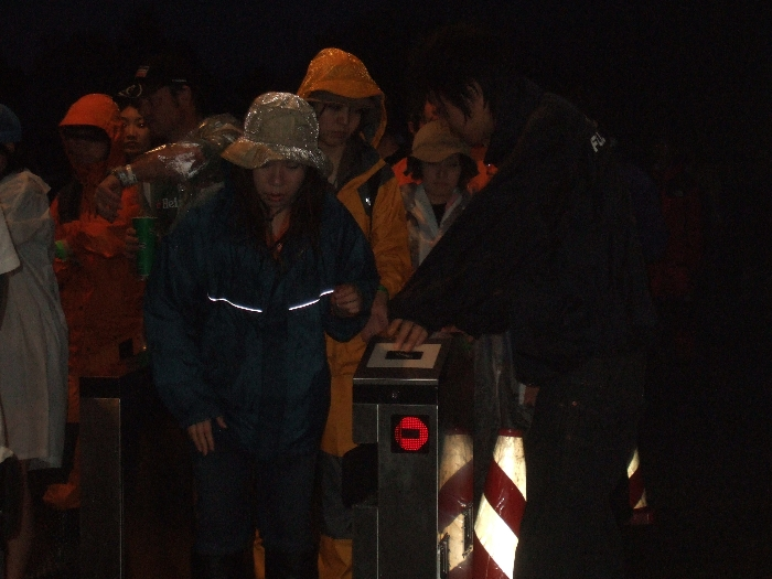 通過すると機械の表示も変わります。駅の改札機とまったく同じです。フジロックフェスティバルでは、荷物を大量に抱える人と手ぶらの人が混在しており、入場ゲートを通過する速度も異なります。したがって機器を一律に制御するのは難しい面があります。フジロックフェスティバルの主催者であるスマッシュは、90年代後半以降の日本のロック・フェスティバルの先駆者であるため、運営ノウハウの蓄積にかなりの投資をしてきたはずです。この改札システムは、将来フジロックフェスティバルに導入することよりも、別のイベントに応用したり、他のイベント会社にシステムごと販売するのが目的ではないかと思われます。リストバンドを携帯電話にしてチケットレスにすれば、ダフ屋撲滅や転売無効化にも生かせる可能性があります。