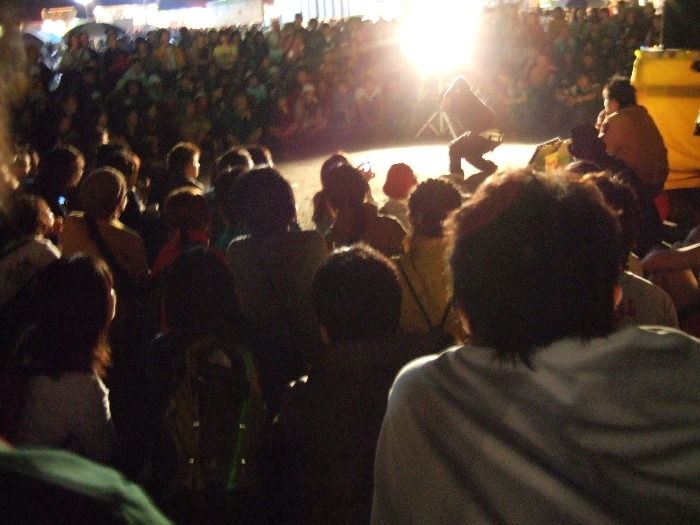 やぐらの下で大道芸をする人。大道芸をする人は何人も来ています。前夜祭は午前0時で終了です。