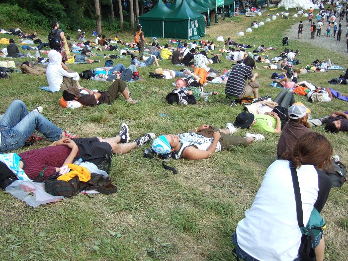アーティスト・グッズ売り場前の斜面。一度にこれだけの人が横になれる場所はほかにないでしょう。グリーン・ステージ後方とは違い、レジャーシートを敷かなくても芝生の上に直接寝られるというのがポイント。 