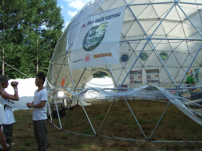 ドームテントの前でWOWOWから取材を受ける人。通風のためドームテントの下の方を開放していますが、閉め切っていると蒸し風呂状態だと思われます。