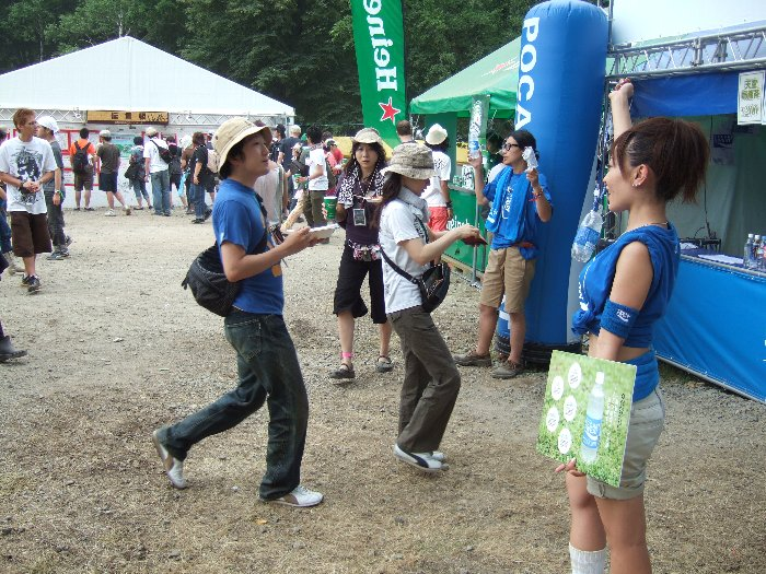 ペットボトルを首から提げるためのストラップも売っています。それを宣伝する女性。 