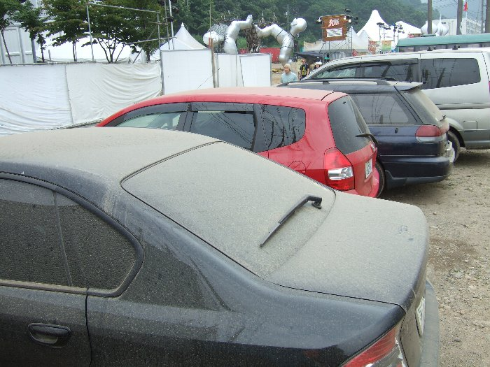 砂ぼこりをかぶった駐車場の車。このくらいの土ぼこりが会場内でも舞っているということです。