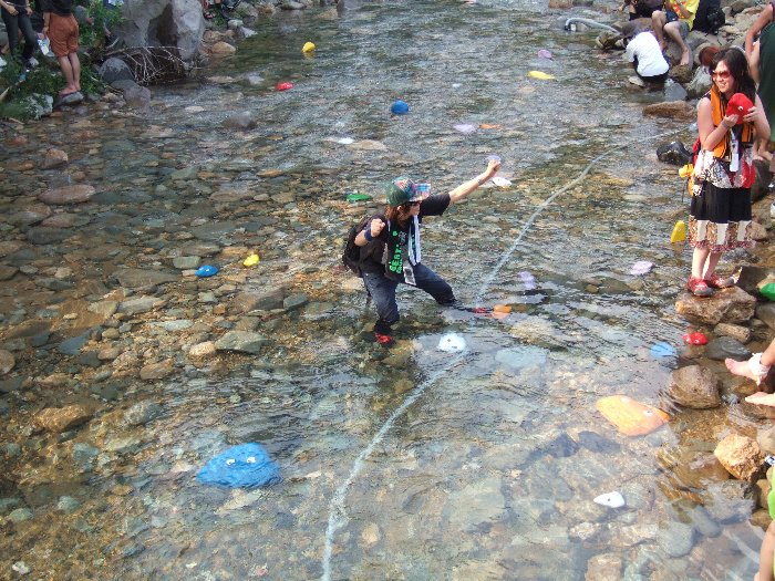 服のまま川に入ってポーズをとる人。