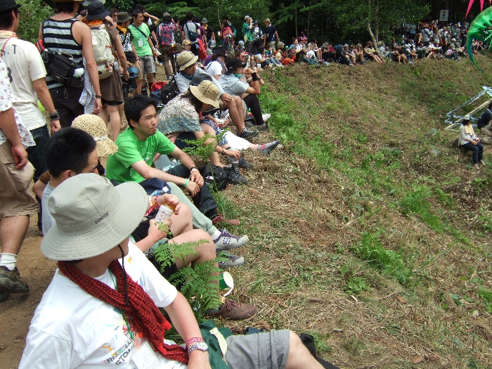 土手からオレンジコートを眺める人たち。 