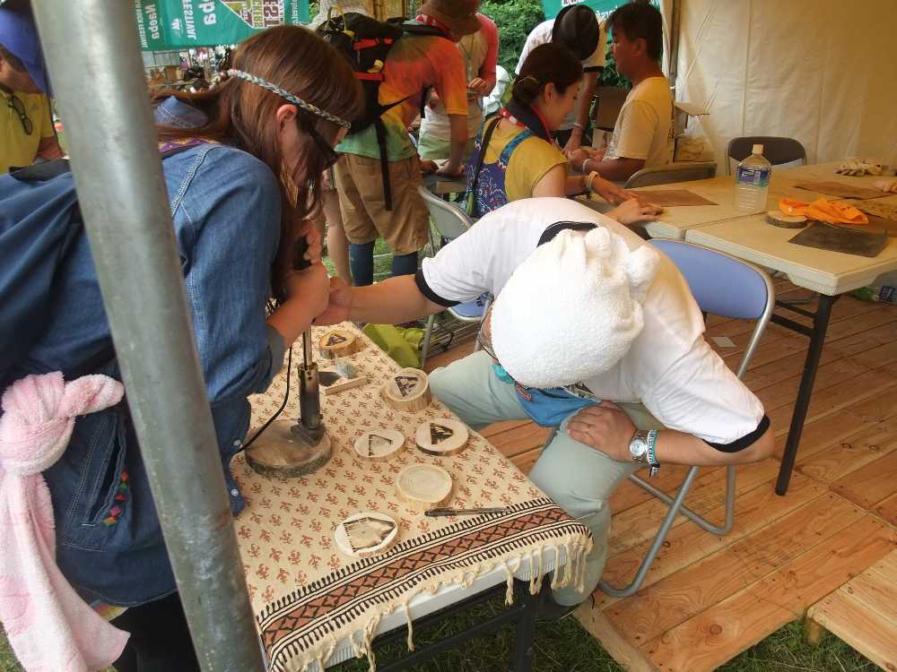 フジロックのマークが入ったコースターらしきものを作っている。