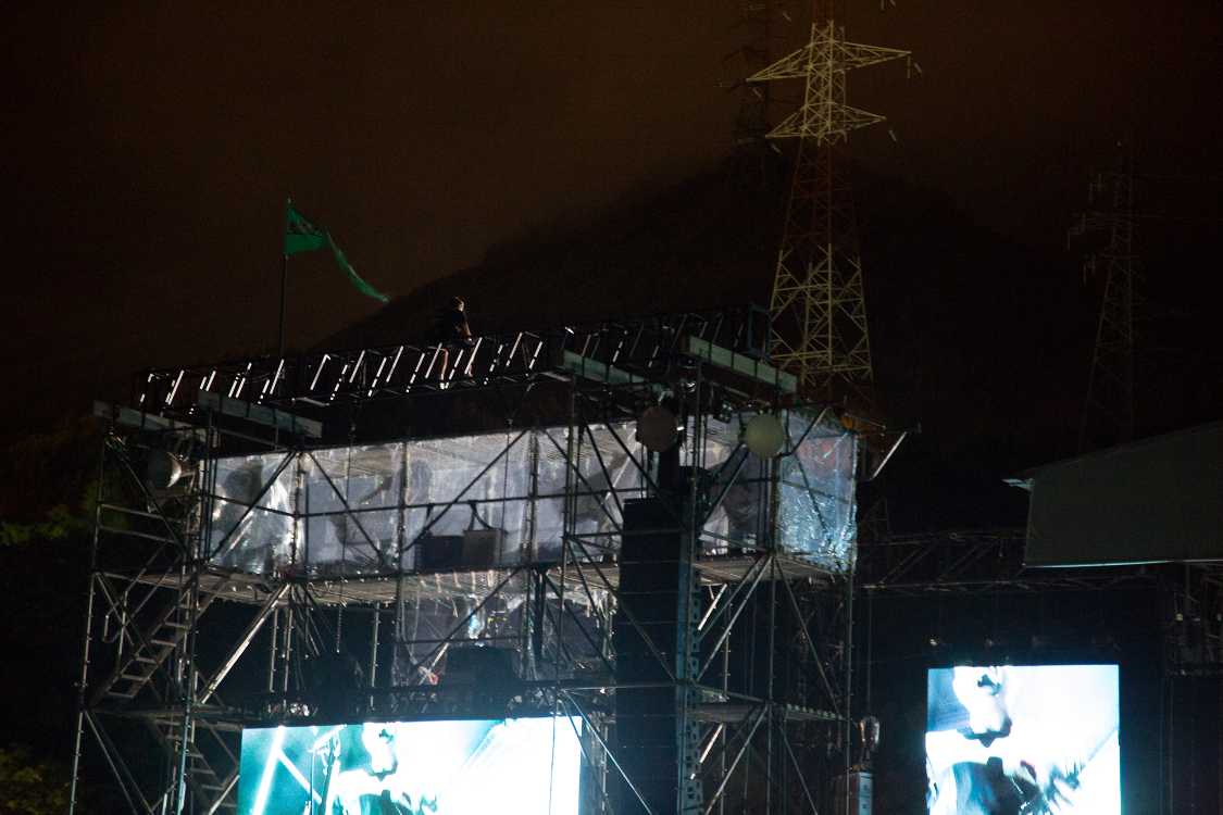 照明タワーの最上部に人が座ってライブを見ていました。