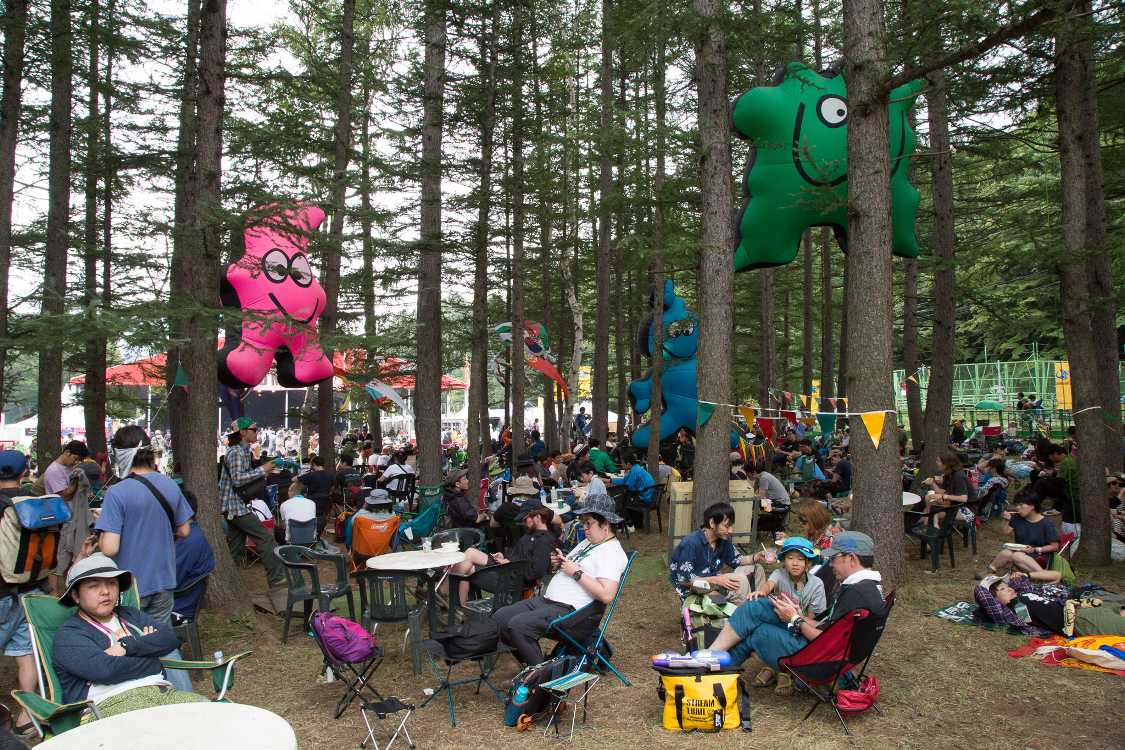 ワールドレストランとレッドマーキーの間の林。テーブルといすが並べられています。