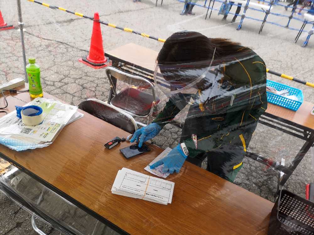 ビニールのカーテン、マスク、手袋、フェイスシールドの厳重な装備。