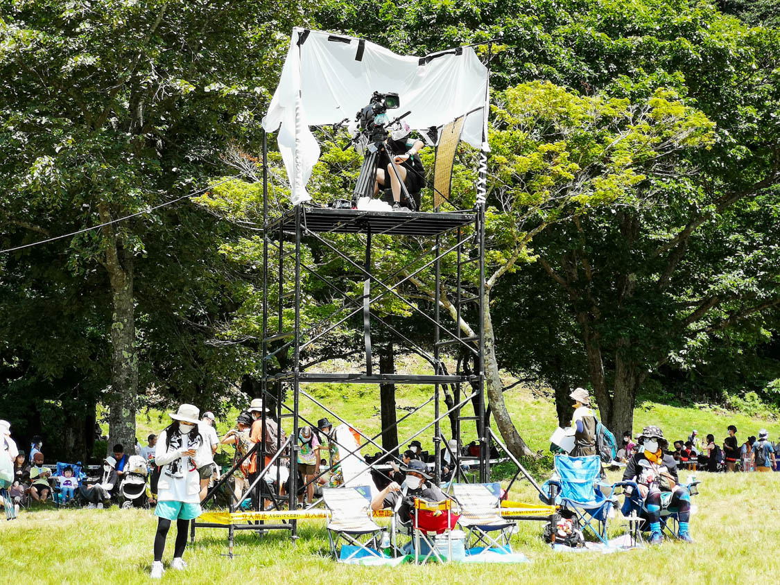 炎天下での映像撮影。強風を考えるとひさしの常設は難しいのでしょう。