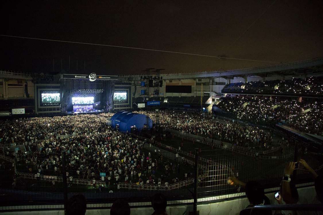 観客がスマートフォンの照明を上に掲げているところ。